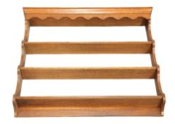 AN OAK PLATE RACK, with shaped apron and three shelves