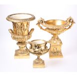 THREE GILT COMPOSITION URNS, each with twin handles. Largest 34cm high