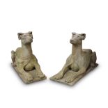 A PAIR OF WEATHERED CARVED STONE MODELS OF RECUMBENT HOUNDS