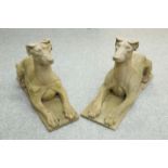 A PAIR OF WEATHERED CARVED STONE MODELS OF RECUMBENT HOUNDS