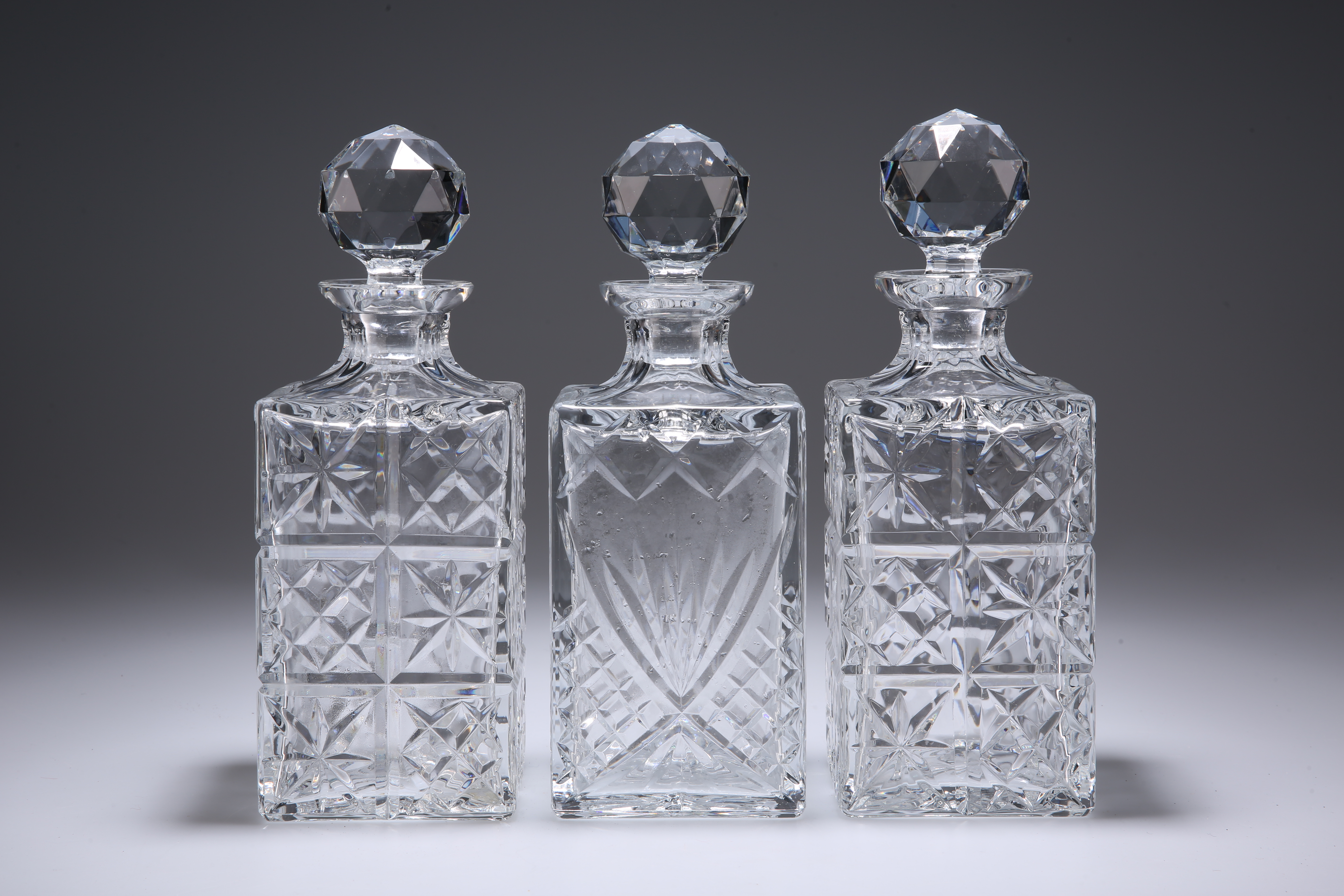 THREE LARGE SQUARE-SECTION GLASS DECANTERS.