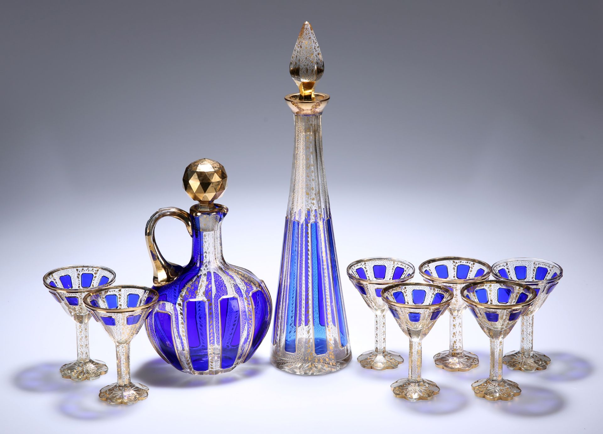 A 19TH CENTURY BOHEMIAN BLUE-OVERLAID AND GILDED CUT-GLASS LIQUEUR SET