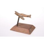 A TRENCH ART METAL MODEL OF A SPITFIRE, on a wooden plinth. 8.6cm high