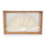 A 19TH CENTURY LACE AND IVORY FAN, in a glazed display case.