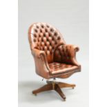 A DEEP-BUTTONED BROWN LEATHER DESK CHAIR, with high back and out-scrolled arms swivelling on an x-