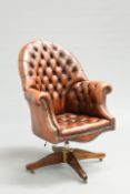 A DEEP-BUTTONED BROWN LEATHER DESK CHAIR, with high back and out-scrolled arms swivelling on an x-