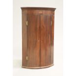 A GEORGE III MAHOGANY BOW-FRONT HANGING CORNER CUPBOARD