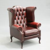 A DEEP-BUTTONED RED LEATHER CHESTERFIELD "QUEEN ANNE" WING CHAIR