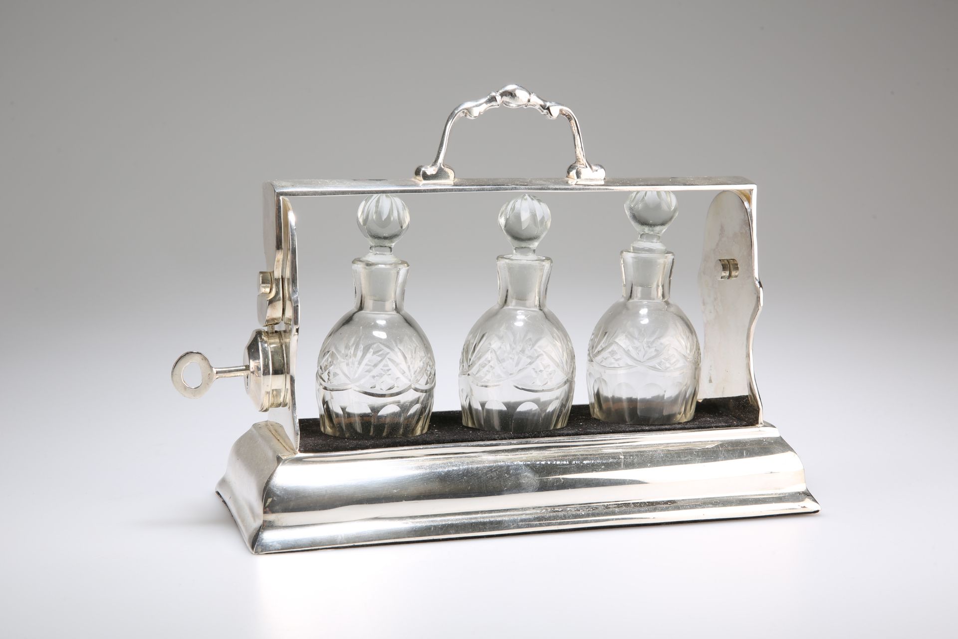 AN EDWARDIAN SILVER-PLATED THREE-BOTTLE TANTALUS