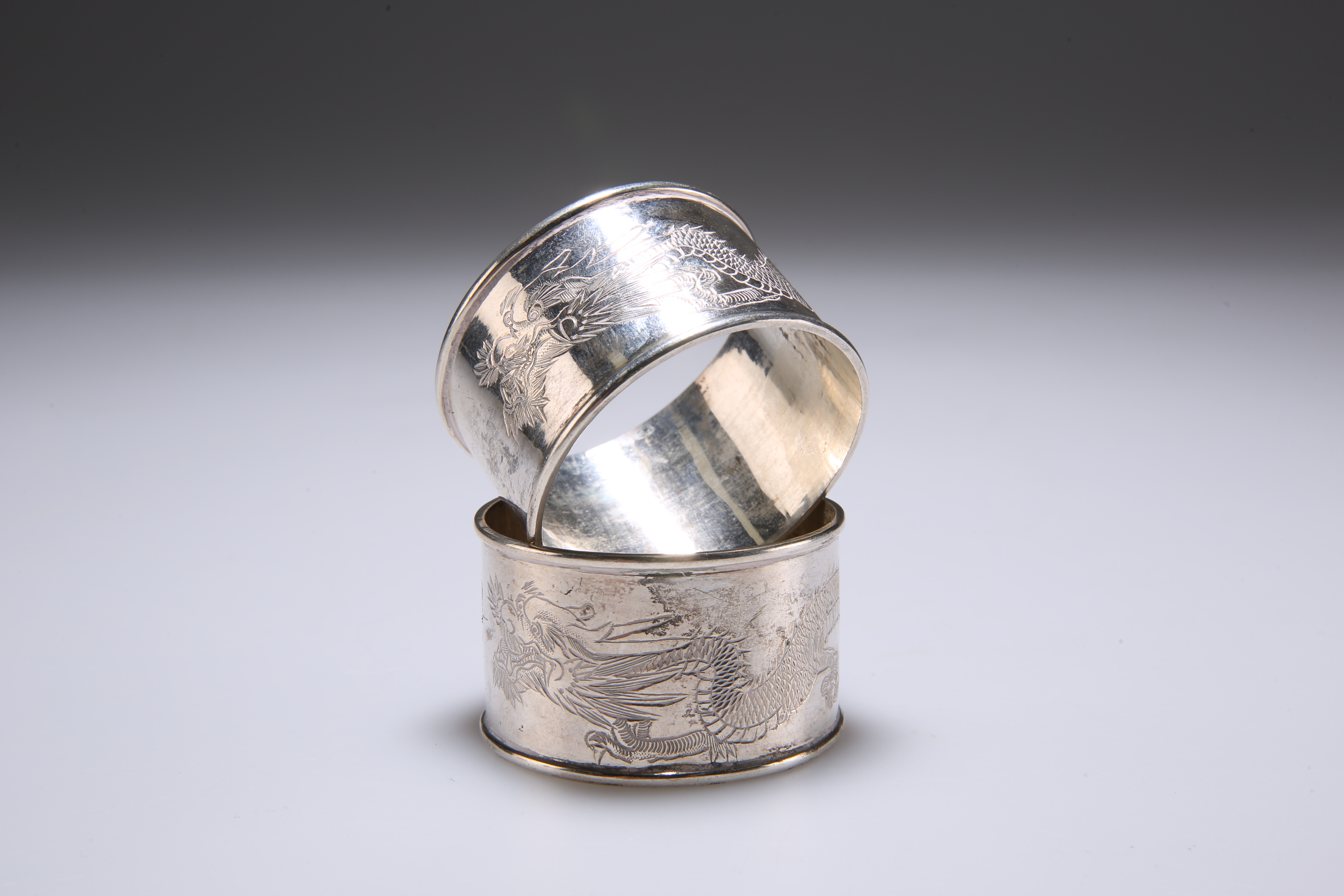 TWO CHINESE SILVER NAPKIN RINGS, of circular form, the central band engraved with a dragon, bears