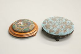 TWO VICTORIAN BEADWORK FOOTSTOOLS, each circular, the first ebonised and with gilt highlighting, the