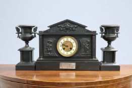 A FRENCH BLACK MARBLE AND PATINATED METAL CLOCK GARNITURE