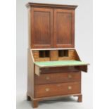 A GEORGE II OAK BUREAU BOOKCASE, the upper section with projecting dentil cornice above a pair of