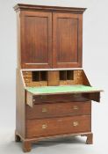 A GEORGE II OAK BUREAU BOOKCASE, the upper section with projecting dentil cornice above a pair of