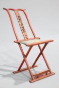 A CHINESE RED LACQUERED FOLDING CHAIR, with footrest and original fabric, central splat carved