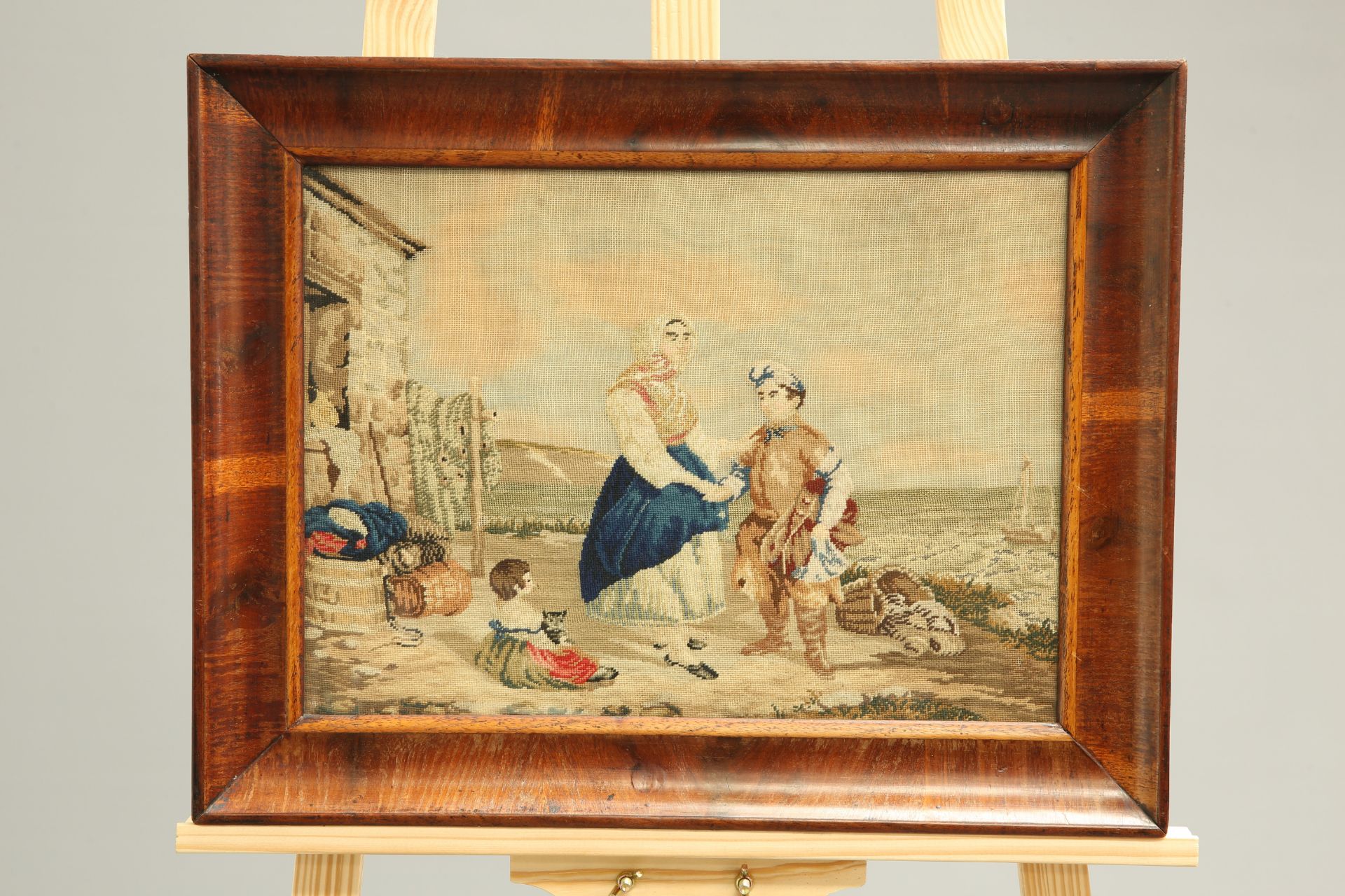 A 19TH CENTURY WOOLWORK PICTURE, depicting a fishing family, in original mahogany frame, overall