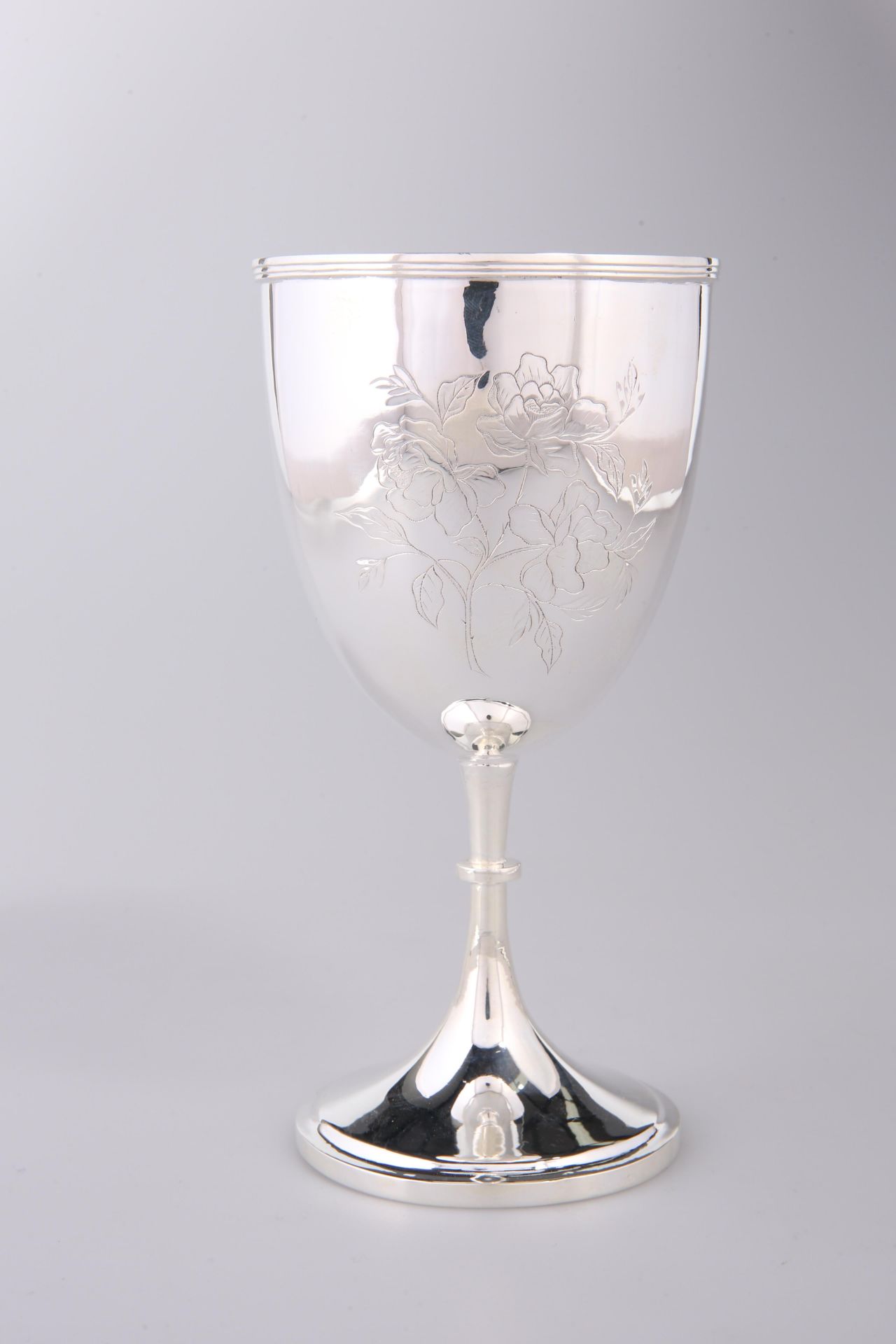 A CHINESE WHITE METAL GOBLET, CIRCA 1900, chased front and back with a floral spray, raised on a