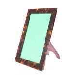 AN EARLY 20TH CENTURY TORTOISESHELL PHOTOGRAPH FRAME, rectangular, with leather easel back. 21.5cm