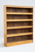 ARTHUR SIMPSON OF KENDAL AN ARTS AND CRAFTS OAK OPEN BOOKCASE, the shelves with hinged flaps,