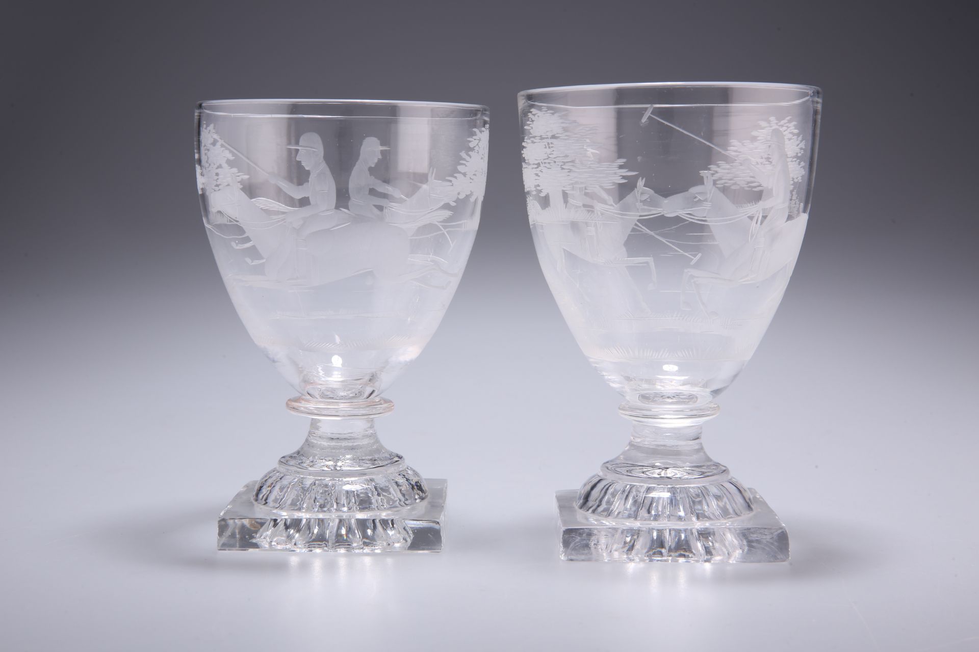 A PAIR OF 19TH CENTURY GLASS RUMMERS, each etched with polo players, raised on square lemon-squeezer