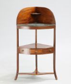 A GEORGE III MAHOGANY CORNER WASHSTAND, the top shelf with cut-outs for bowls and now glazed over,