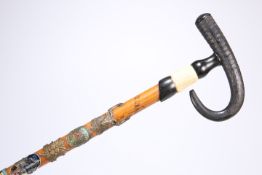 AN EARLY 20TH CENTURY CANE, with ebonised horn-form handle, applied with badges and inscribed '