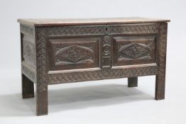 A LATE 17TH CENTURY OAK COFFER, the lid carved with scrolling foliage above a panelled case with