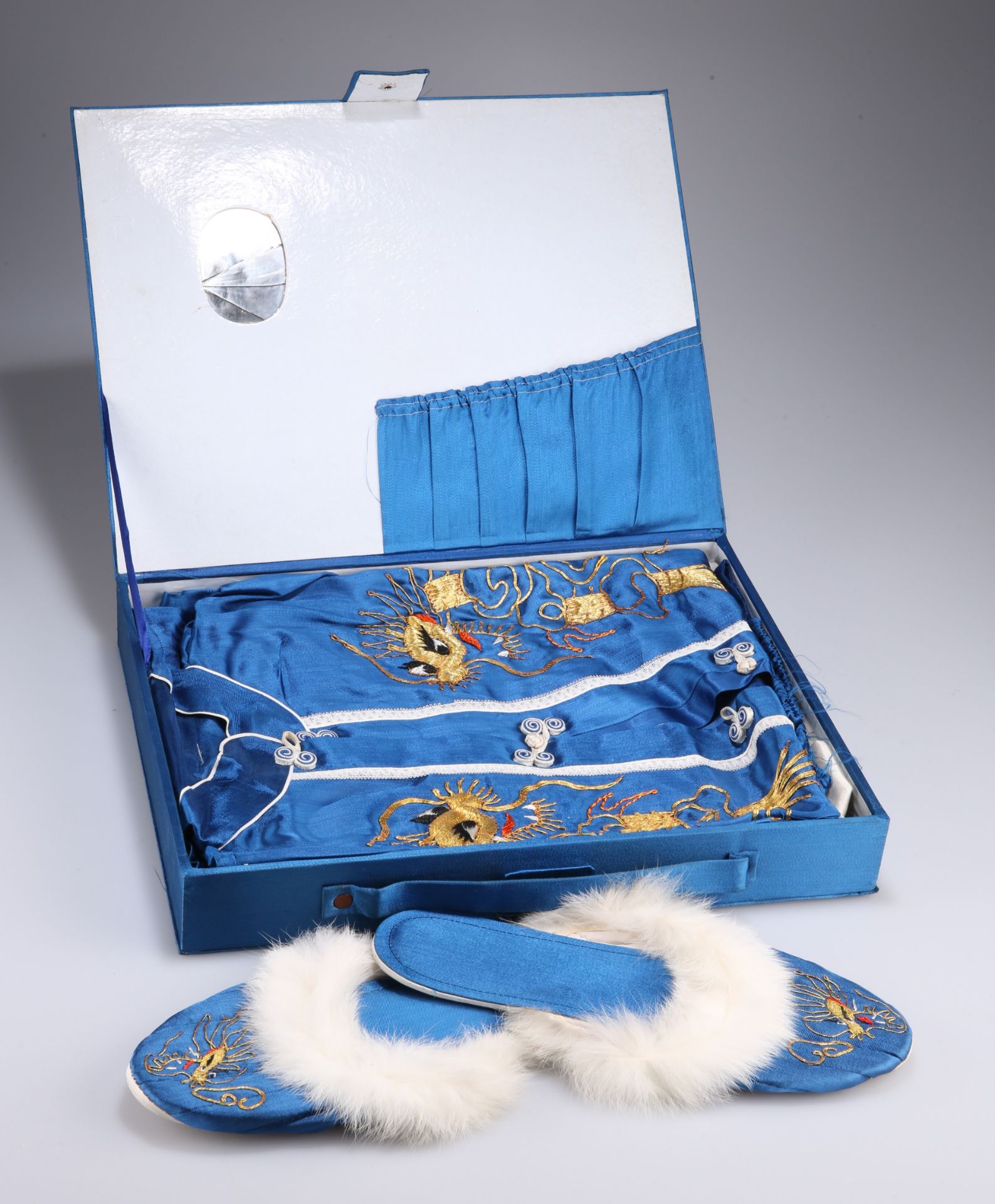 A CHINESE BOXED SET OF BLUE SILK PYJAMAS, GOWN AND SLIPPERS, worked in relief with coloured