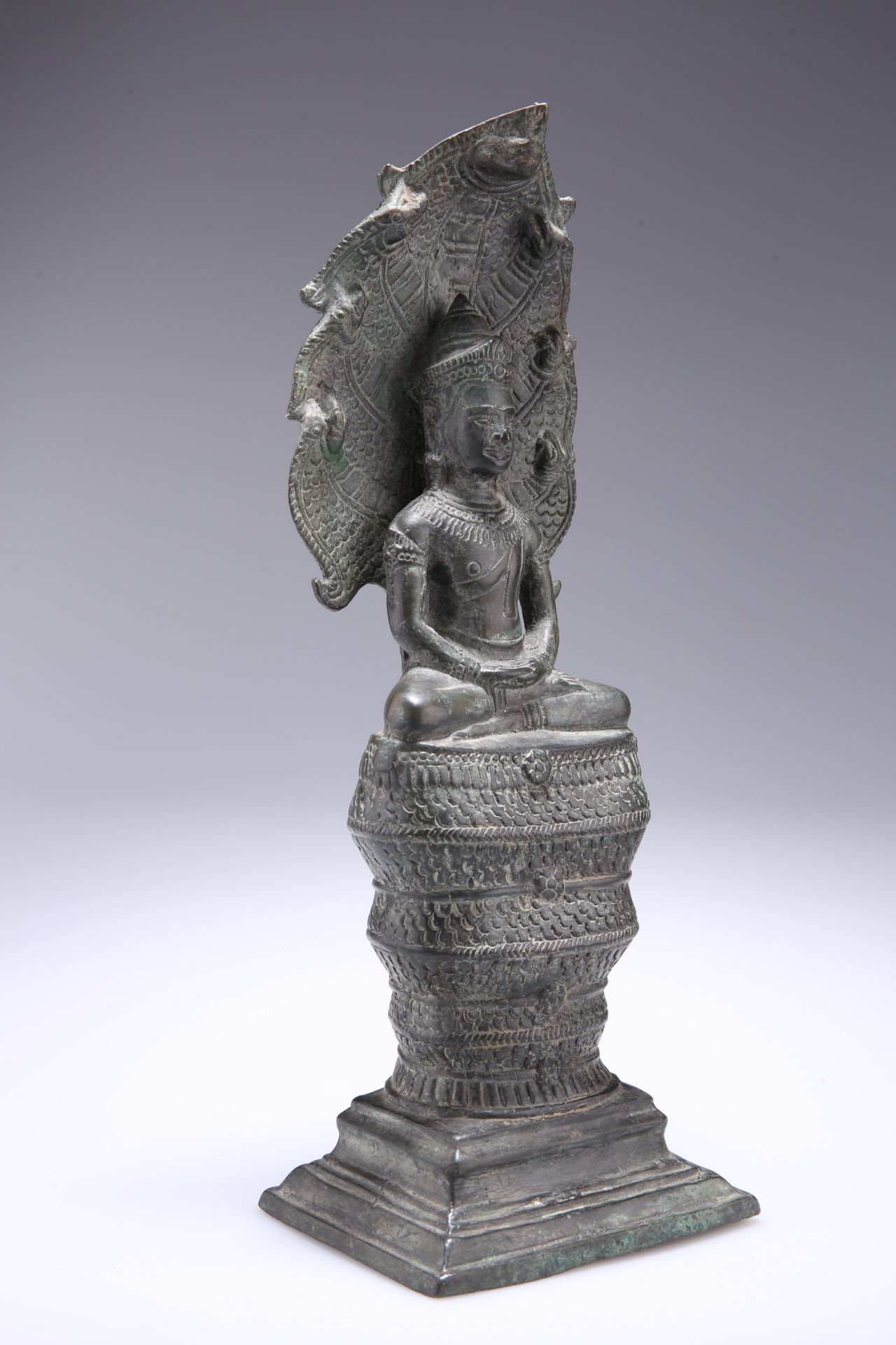 A CAMBODIAN BRONZE BUDDHA, seated with Naga, 18th Century. 33.5cm