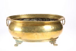 A GEORGIAN STYLE OVAL BRASS WINE COOLER, EARLY 20TH CENTURY, with ring handles and paw feet. 40.