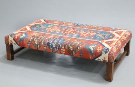 A LARGE KILIM STOOL, rectangular, raised on square-section legs joined by an H-stretcher. 152cm by