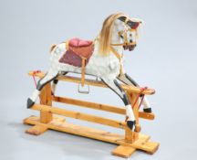 AN EDWARDIAN PAINTED ROCKING HORSE, with saddle and bridle, on a pitch-pine stand. 109cm high to tip