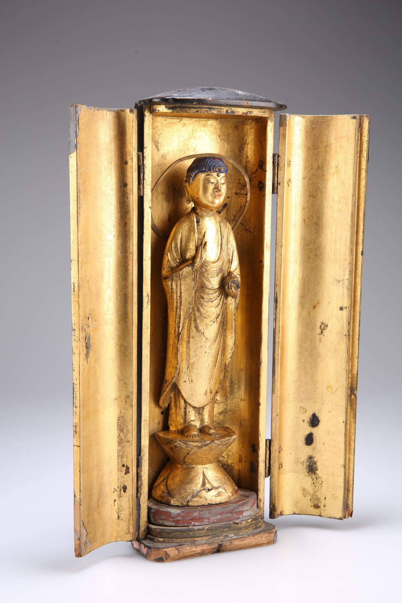 A CHINESE GILDED AND LACQUERED FIGURE OF A BUDDHA, carved standing on a lotus-leaf form base, fitted