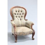 A VICTORIAN MAHOGANY SPOONBACK ARMCHAIR, the deep button back with carved crest, raised on scroll