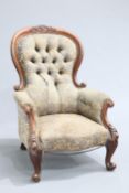 A VICTORIAN MAHOGANY SPOONBACK ARMCHAIR, the deep button back with carved crest, raised on scroll