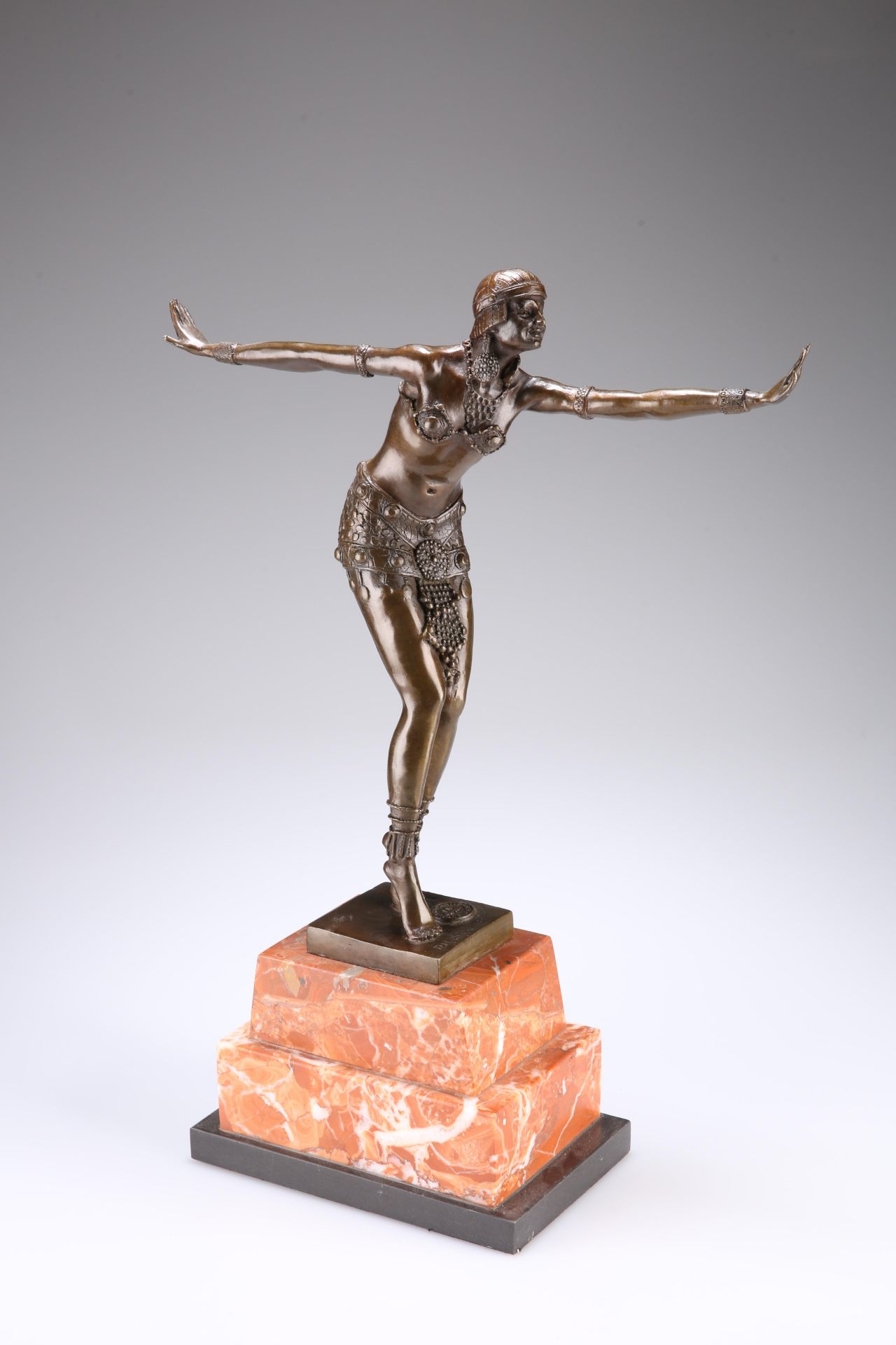 AN ART DECO STYLE BRONZE FIGURE OF A DANCER, in Ballet Russe costume, posing with arms