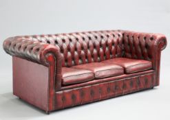 AN OX-BLOOD LEATHER THREE-SEATER CHESTERFIELD SOFA, with deep-buttoned back and arms, moving on