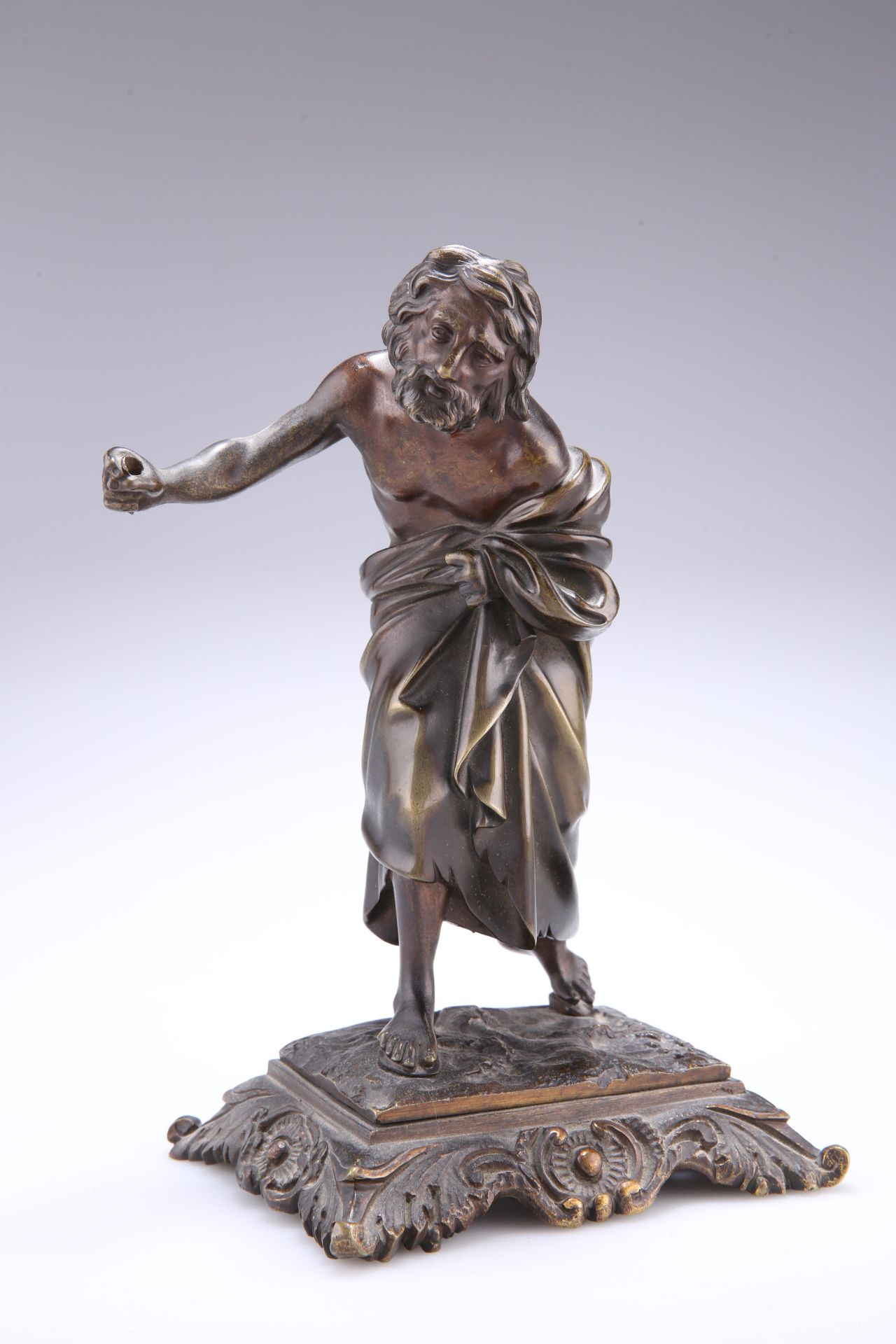 A 19TH CENTURY BRONZE FIGURE, cast as a peasant clutching his robes and with an arm outstretched.