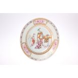 A CHINESE FAMILLE ROSE PLATE, circular, painted with two figures in an interior, within a broad