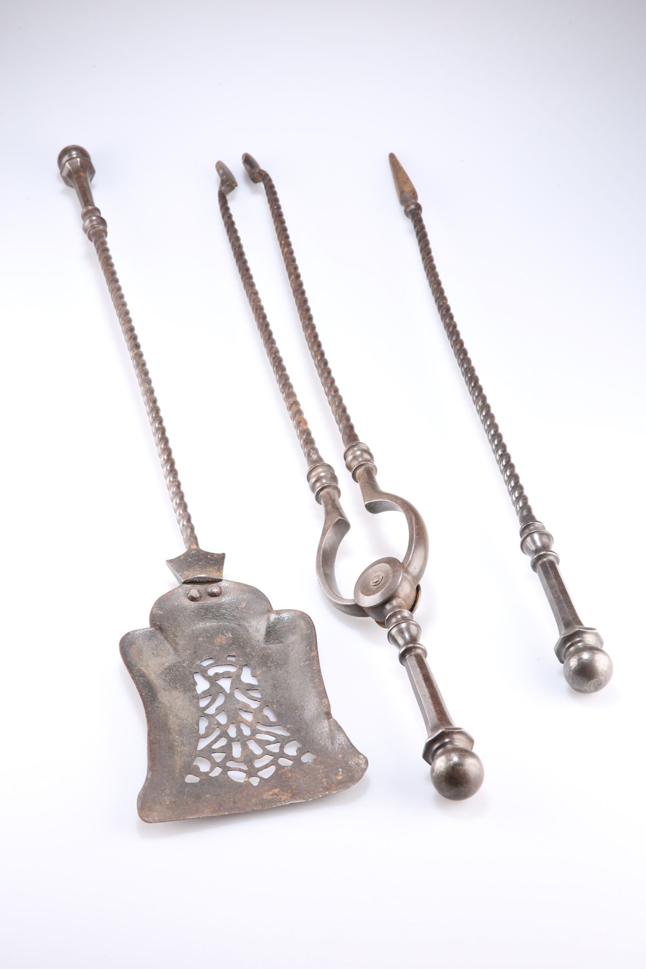 A SET OF 19TH CENTURY STEEL FIRE IRONS, comprising shovel, tongs and poker, each with faceted handle