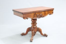 A VICTORIAN MAHOGANY FOLDOVER TEA TABLE, the square top swivelling above a frieze carved with c-
