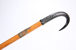 AN EARLY 20TH CENTURY CANE WITH HORN HANDLE, applied with metal plaque depicting two Chamois and