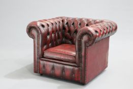 AN OX-BLOOD LEATHER CHESTERFIELD ARMCHAIR, with deep-buttoned back and sides, moving on castors.