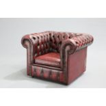 AN OX-BLOOD LEATHER CHESTERFIELD ARMCHAIR, with deep-buttoned back and sides, moving on castors.