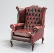 AN OX-BLOOD LEATHER CHESTERFIELD WING-BACK ARMCHAIR, with deep buttoned back and arms, raised on