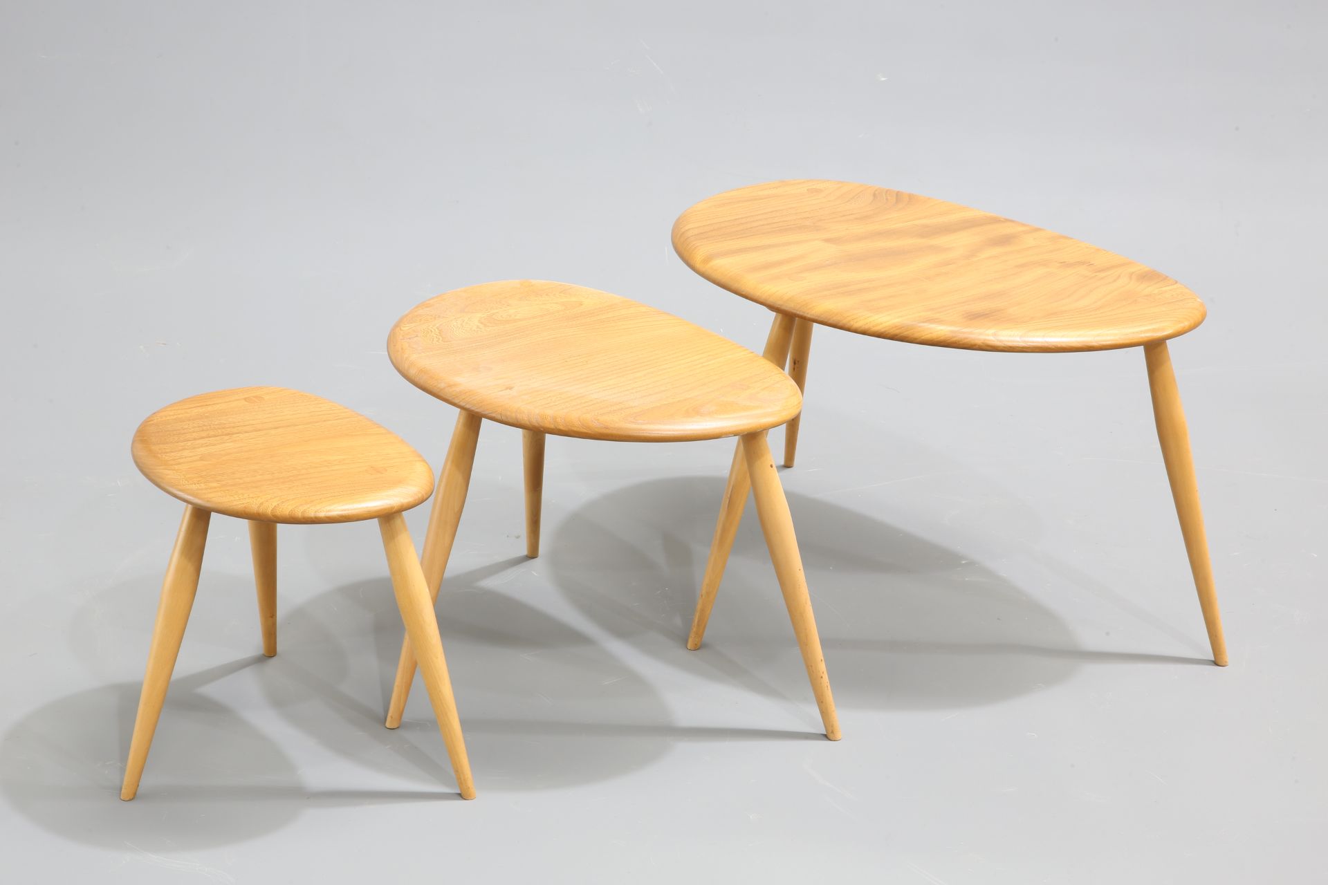 A NEST OF THREE ERCOL BLONDE ELM AND BEECH 'PEBBLE' TABLES, model 354, each labelled. Largest 65cm