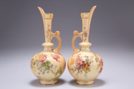 A PAIR OF ROYAL WORCESTER BLUSH IVORY EWERS, each with tapering neck and globular body, painted with