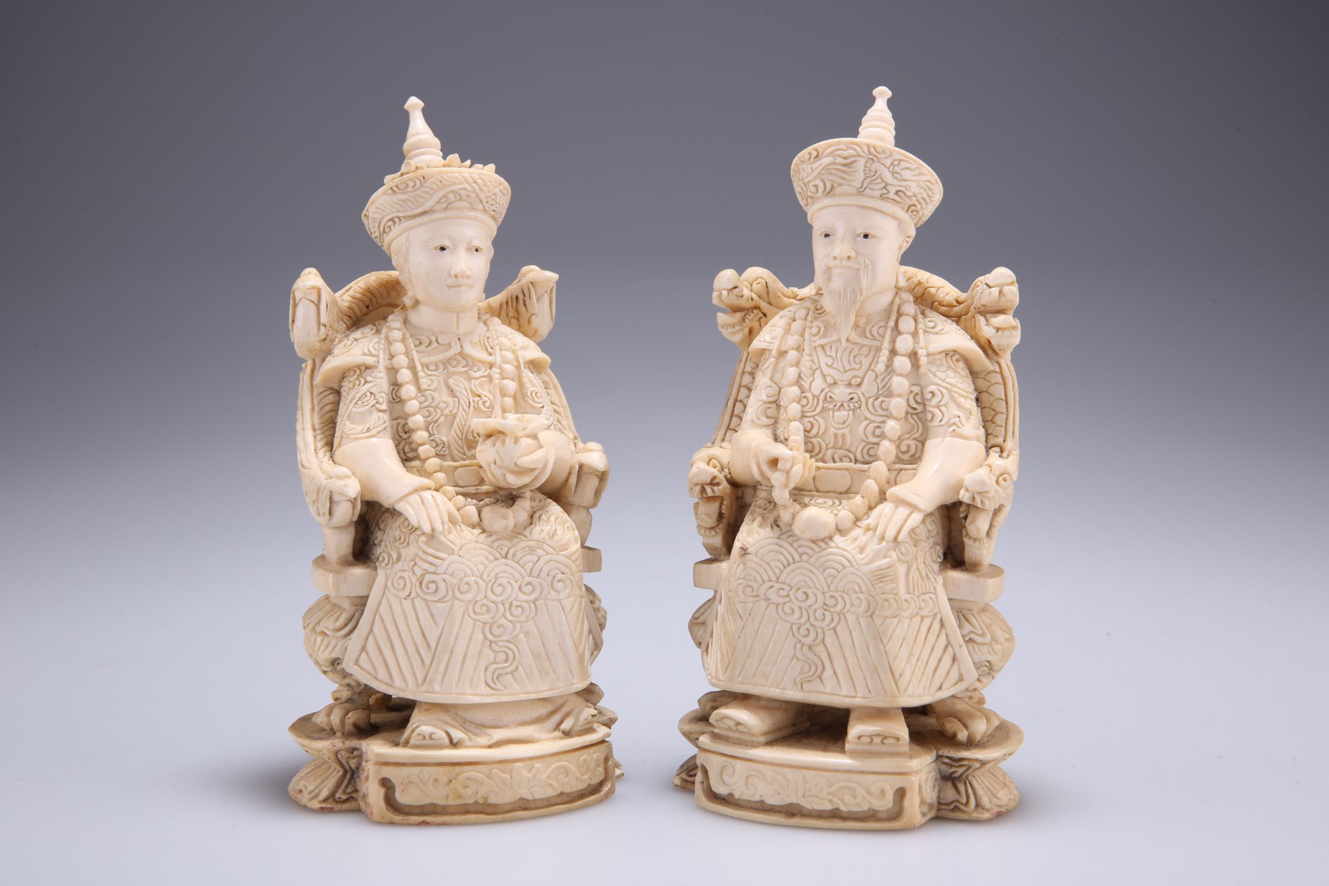 A PAIR OF CHINESE IVORY FIGURES, 19TH CENTURY, carved as a seated emperor and empress, each bears