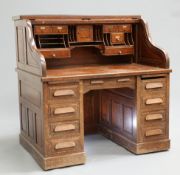 ~ AN EARLY 20TH CENTURY OAK ROLL TOP DESK BY MAPLE & CO., the sliding tambour opening to reveal a