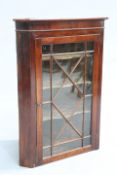 A GEORGE III MAHOGANY GLAZED HANGING CORNER CABINET,  with astragal glazed door enclosing shaped